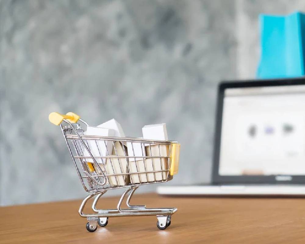 Small shopping cart on a desk next to a laptop